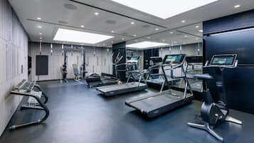 Un gimnasio moderno con cintas de correr, una banca para pesas y una máquina de remo.