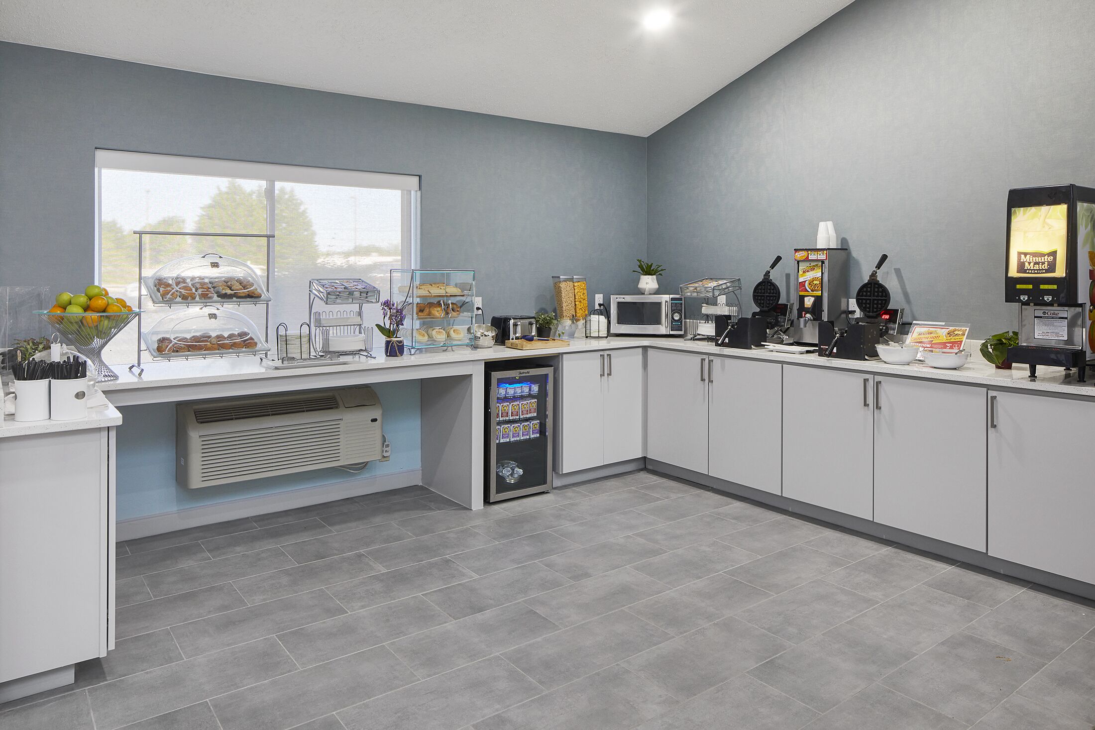 A modern kitchen with a large window, a microwave, waffle maker, and a vending machine.