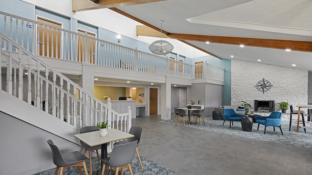 A spacious indoor area with a staircase, a dining area with chairs and a table, and a seating area with sofas and a fireplace. - Hotel Wave Rehoboth Beach (Rehoboth Beach)