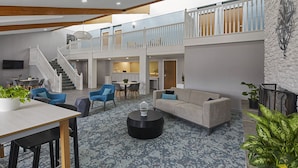 A spacious indoor area with a staircase leading to an upper level, a dining area, and a seating area with a sofa and coffee table. - Hotel Wave Rehoboth Beach (Rehoboth Beach)