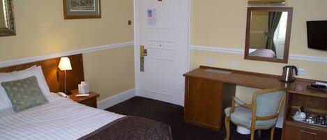 Une chambre d’hôtel équipée d’un lit, d’un bureau, d’une chaise, d’un miroir et d’une télévision.