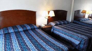 Een hotelkamer met twee bedden, elk voorzien van een houten hoofdbord en een nachtkastje met een lamp.