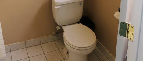 A small bathroom with a toilet, a shelf with towels, and a window.