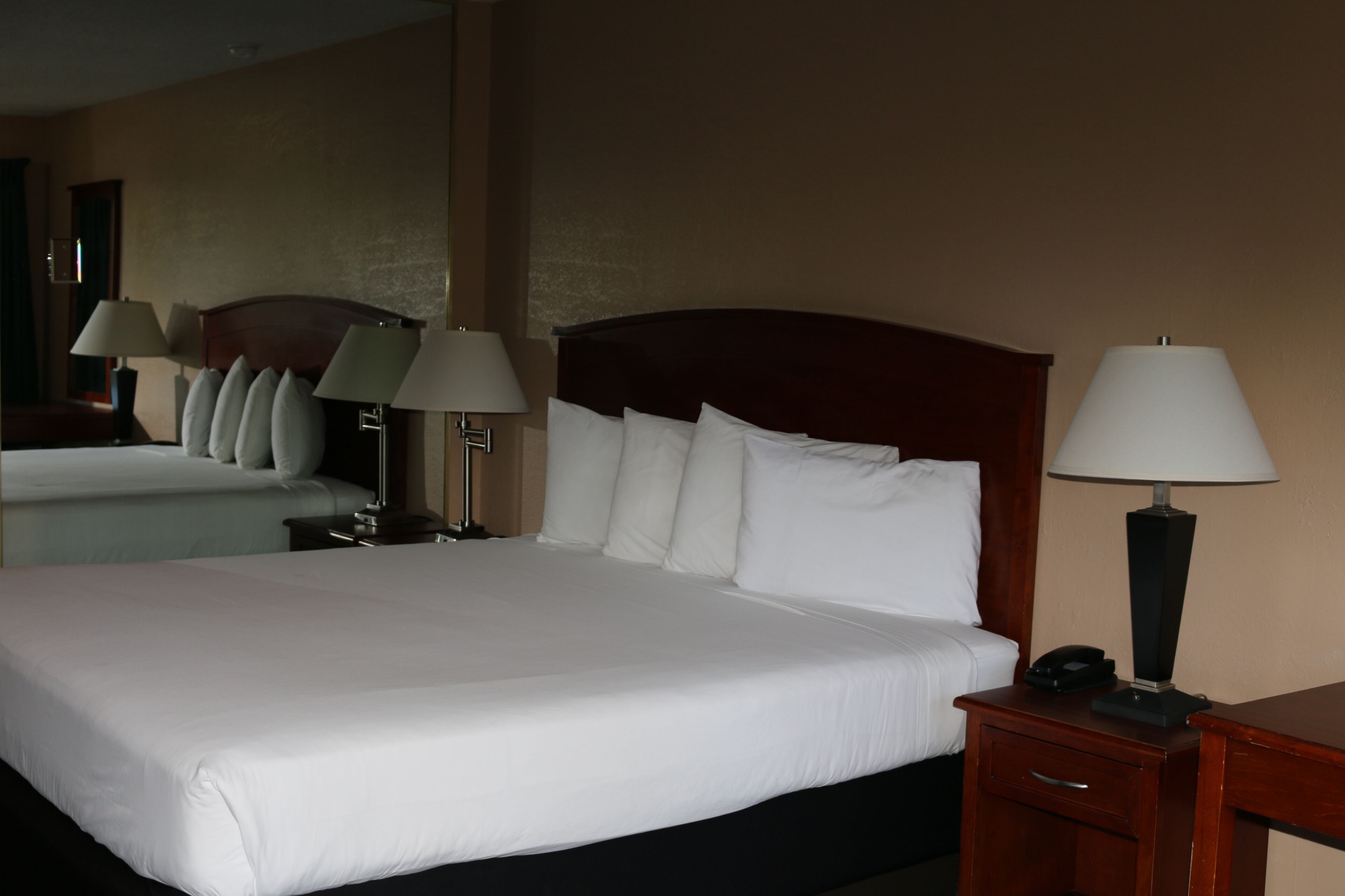 A hotel room with a large bed, two bedside tables, and two lamps.