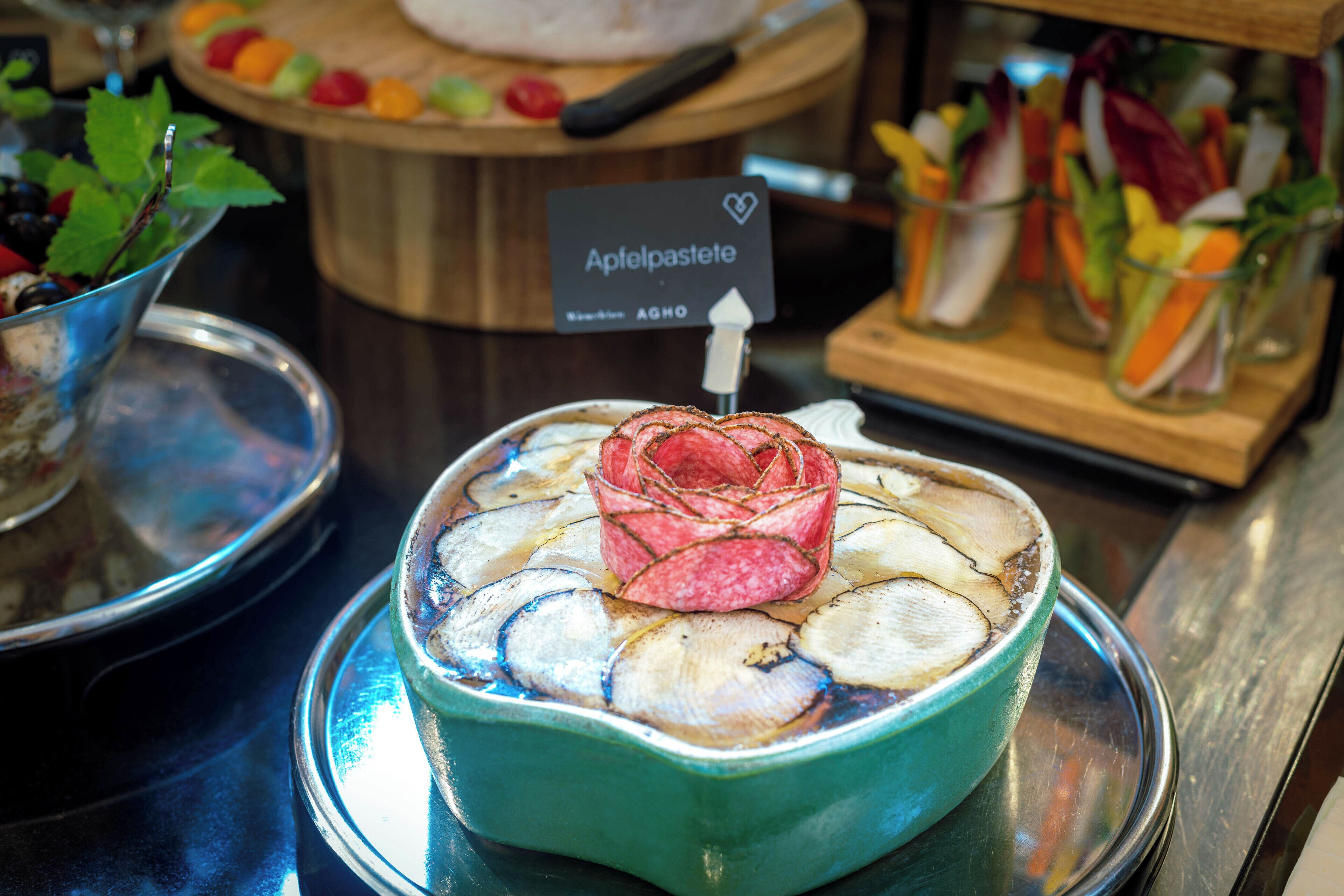 A dish with sliced vegetables and a pink garnish on a ceramic plate.