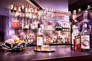 Angolo bar con diverse bottiglie di liquori e bicchieri.