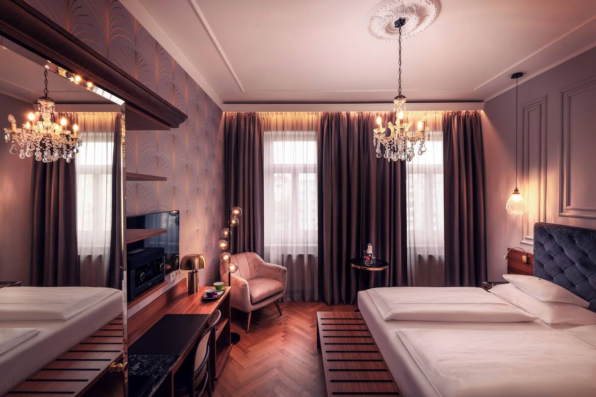 Una habitación de hotel con una cama, un escritorio con televisor, una silla y una araña.