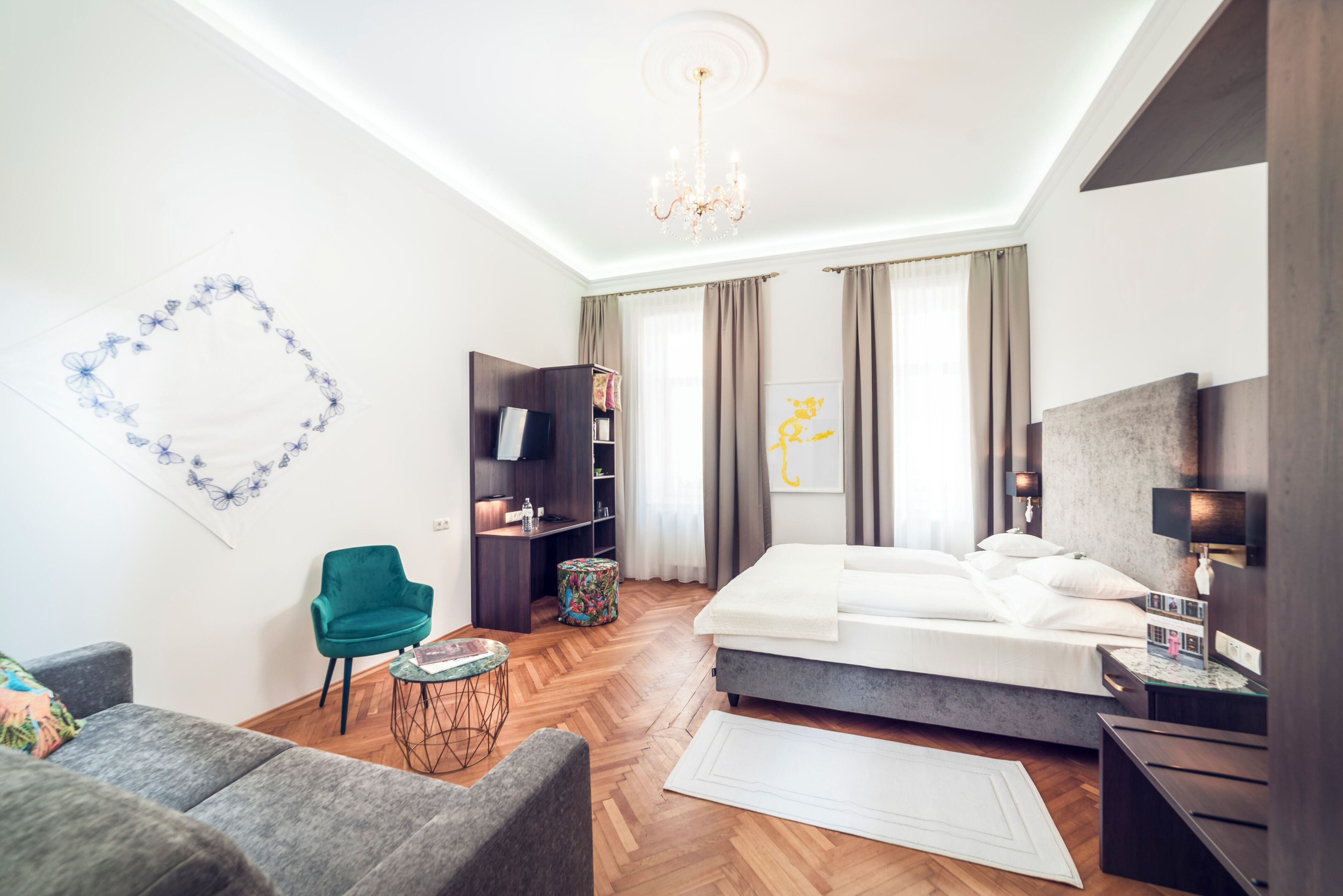 Ein modernes Hotelzimmer mit Bett, Schreibtisch, Stuhl und Fernseher.