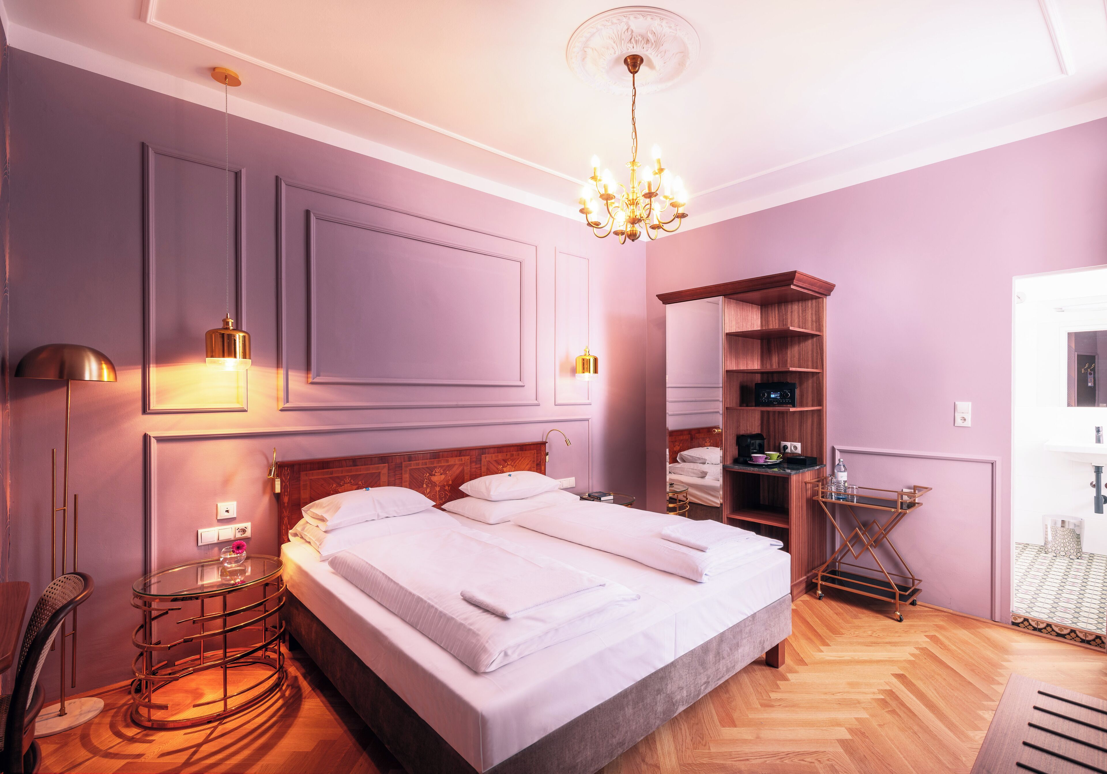A bedroom with a large bed, bedside tables, a wardrobe, and a chandelier.