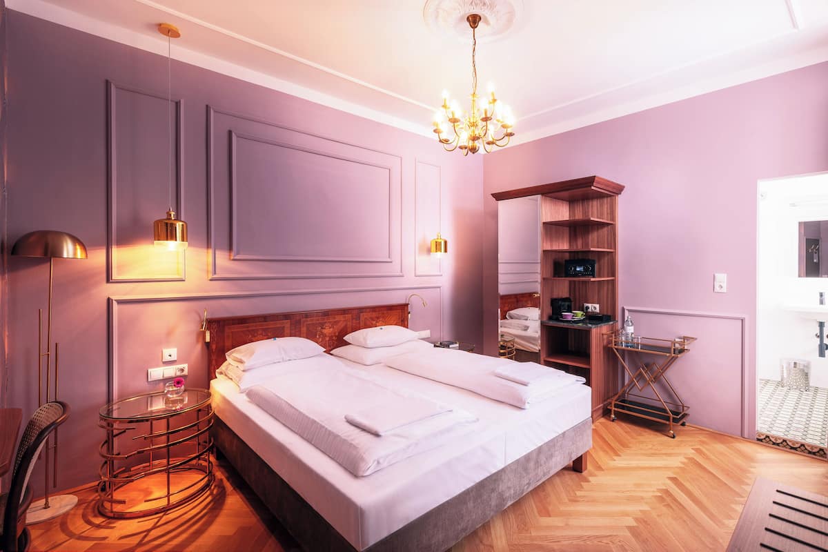 Une chambre à coucher avec un grand lit, des tables de chevet, une armoire et un lustre.