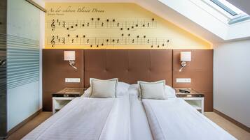 A hotel room with a large bed, two bedside tables, a wall-mounted lamp, and a skylight.