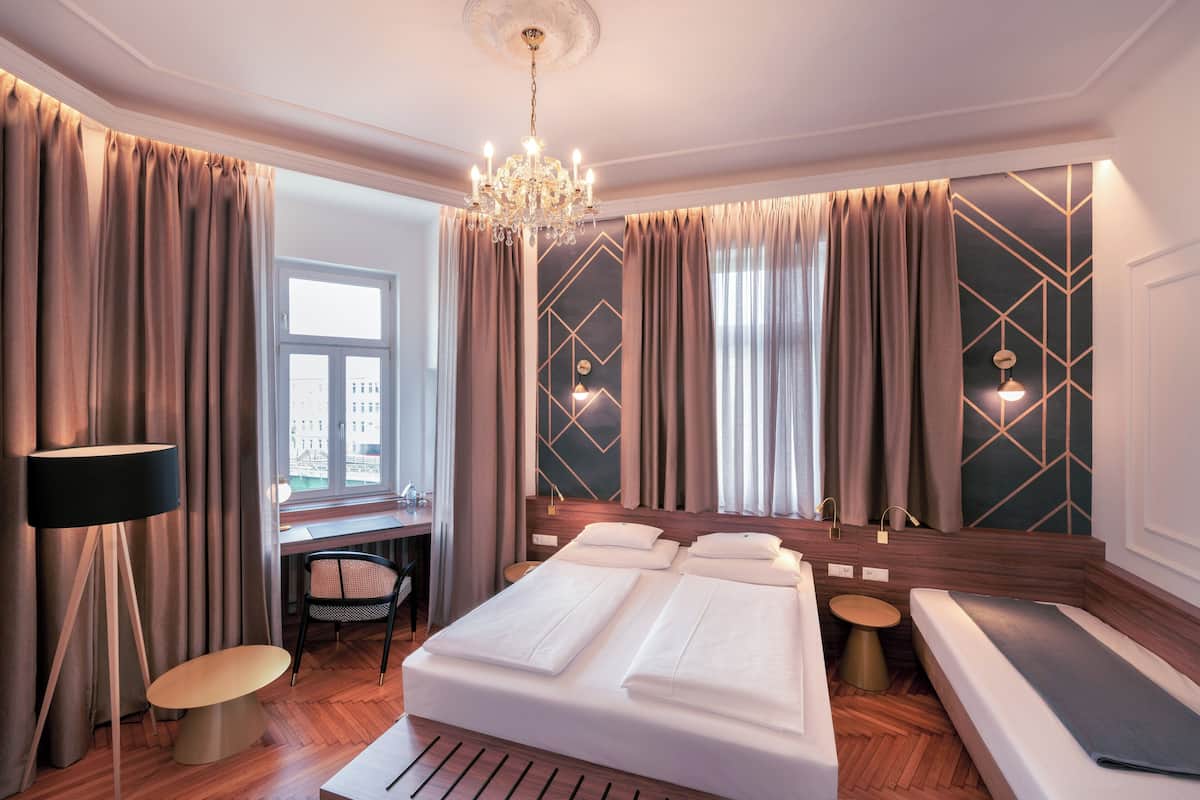 Una habitación de hotel con una cama grande, un escritorio, una silla, una mesa de masaje y un candelabro.