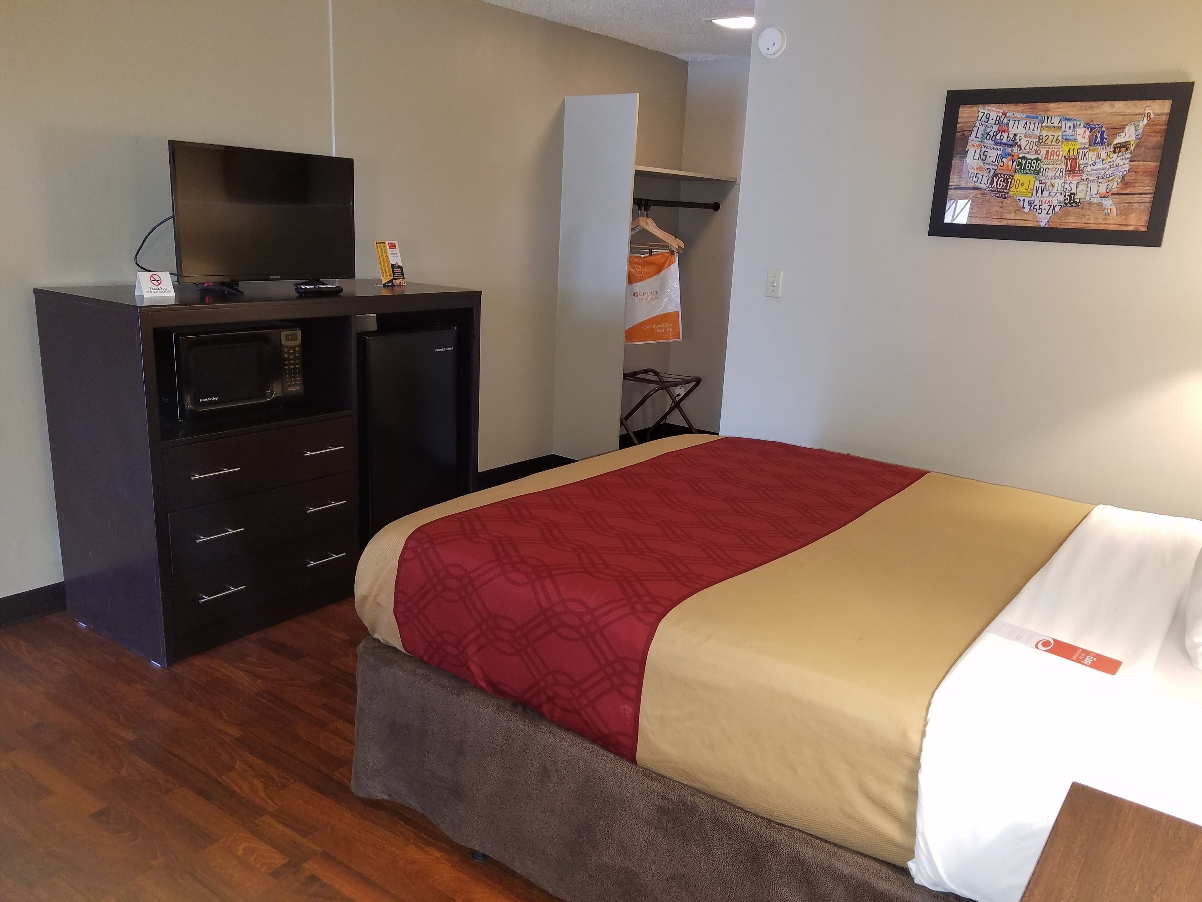 Habitación de hotel con cama, televisor, microondas y refrigerador.