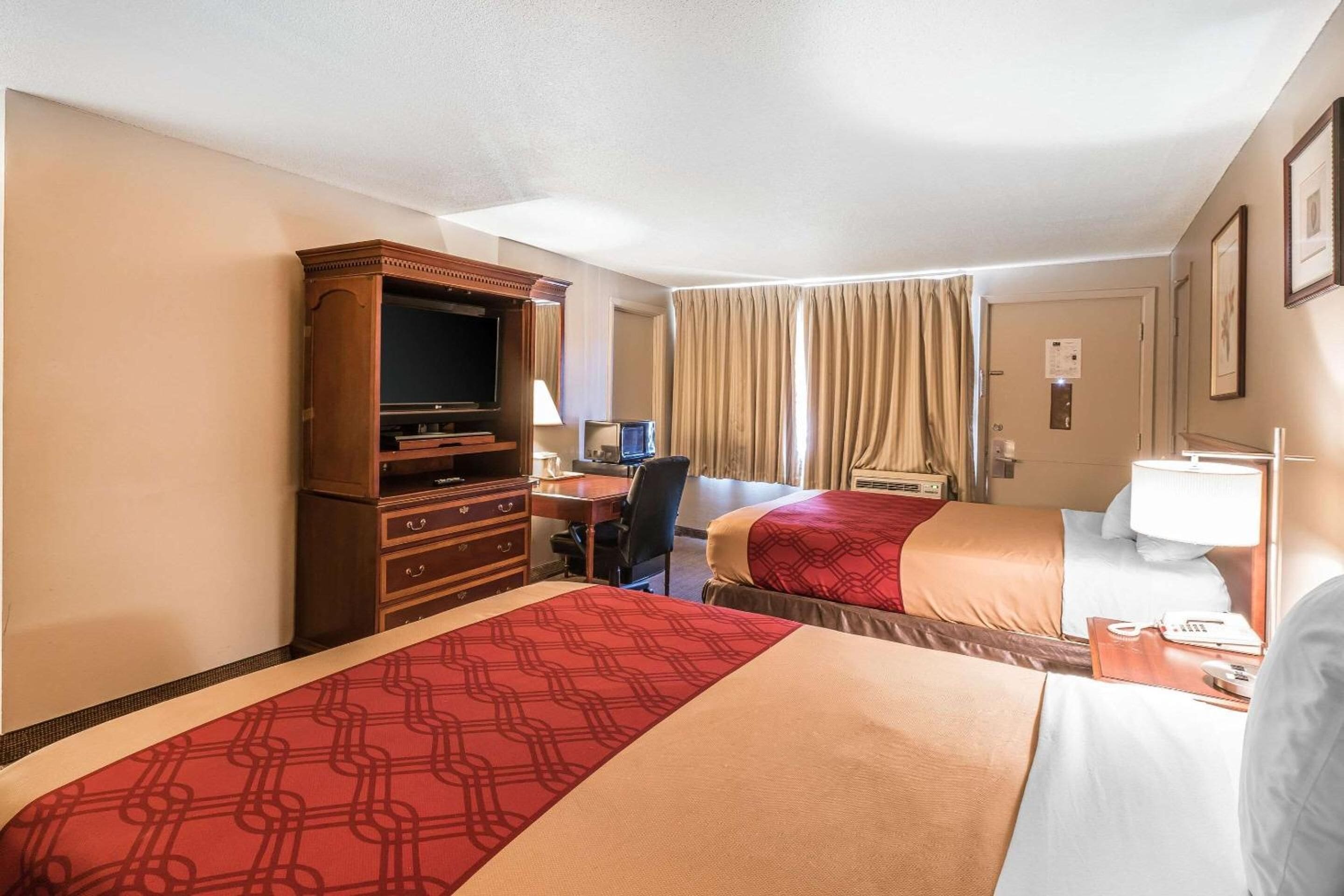 Habitación de hotel con dos camas, un escritorio con computadora, televisor y minibar.