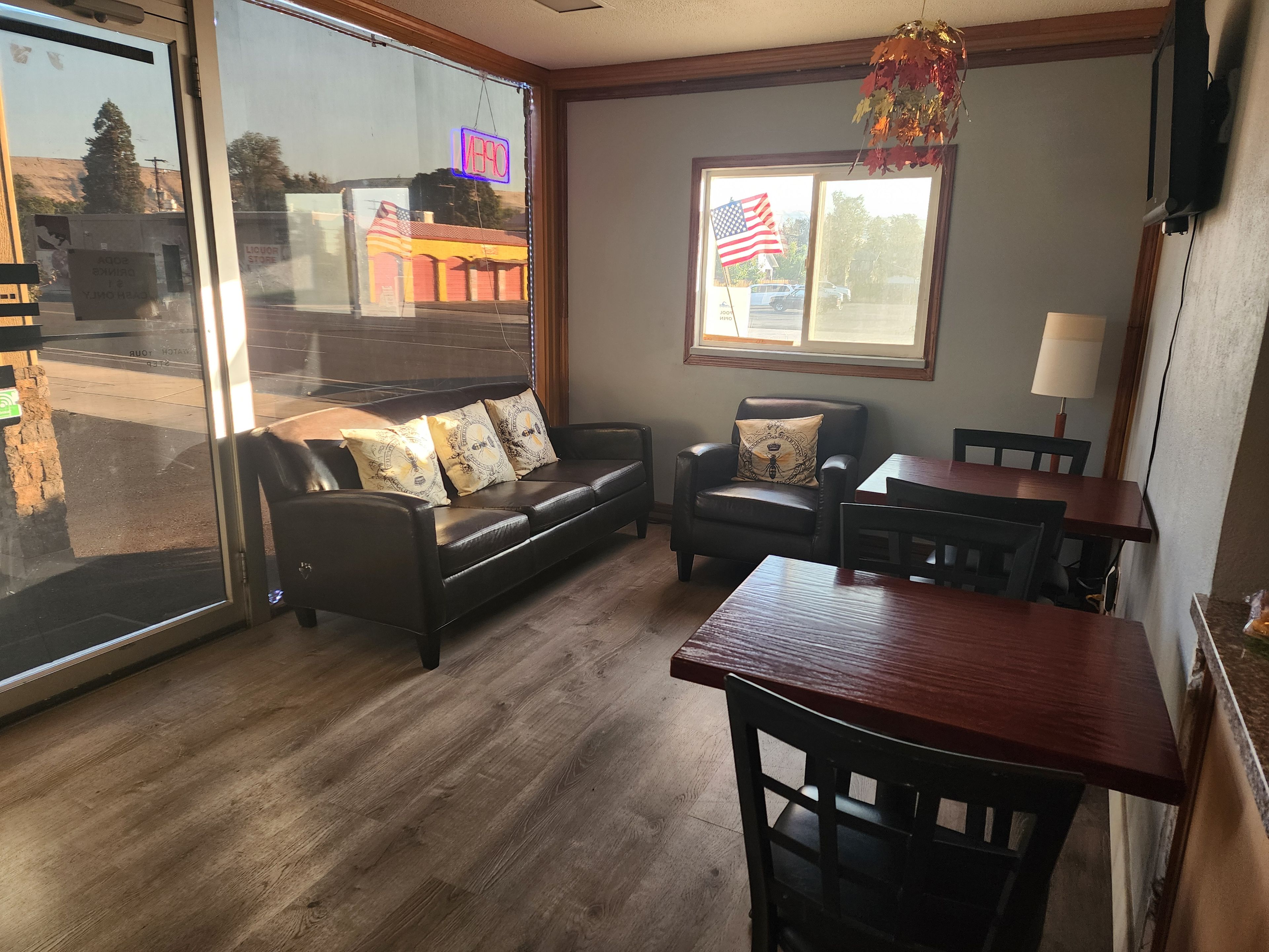Una habitación con un sofá de cuero, una mesa de comedor de madera y una ventana con una bandera estadounidense.