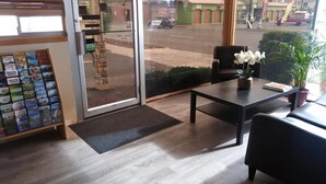 A reception area with a glass door, a small desk with a vase of white flowers, and a display of cannabis products. - Holiday Lodge Yakima (Yakima)