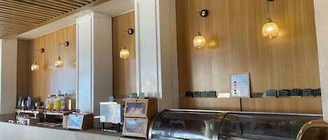 Una barra de desayuno con techo de madera, luces colgantes y una pizarra con el menú.