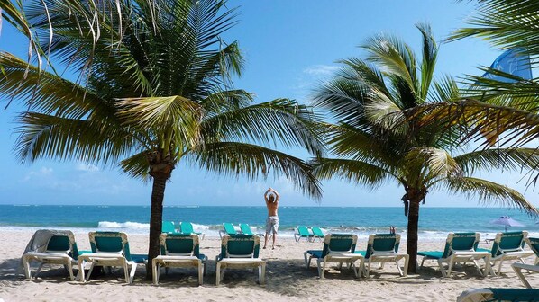 On the beach, white sand, sun loungers, beach towels