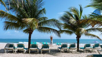 Na praia, areia branca, espreguiçadeiras, toalhas de praia 