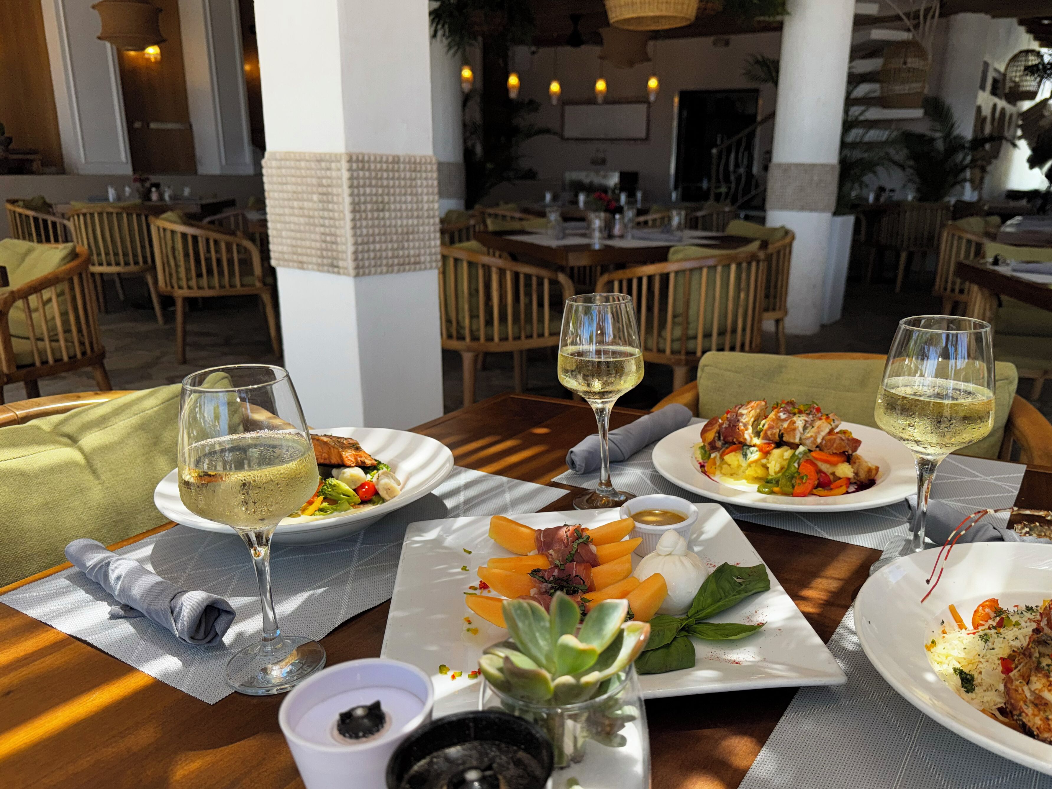Una tavola imbandita con piatti di cibo, bicchieri di vino e una piccola ciotola di salsa.