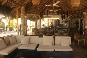 A covered outdoor seating area with wicker furniture and a bar. - Hotel Villa Taina (Cabarete)