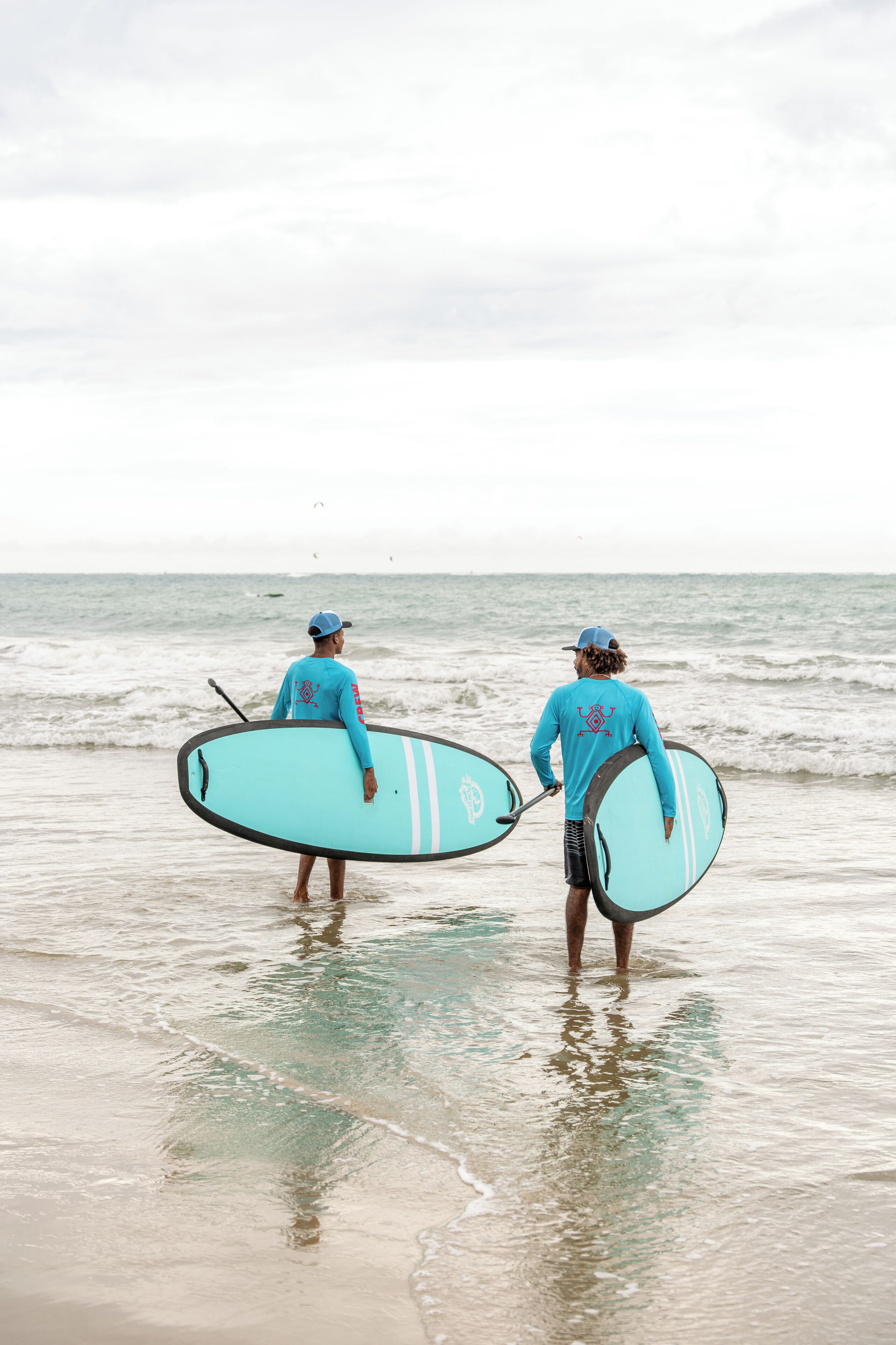 Deux personnes se promènent sur une plage, portant des planches de surf.