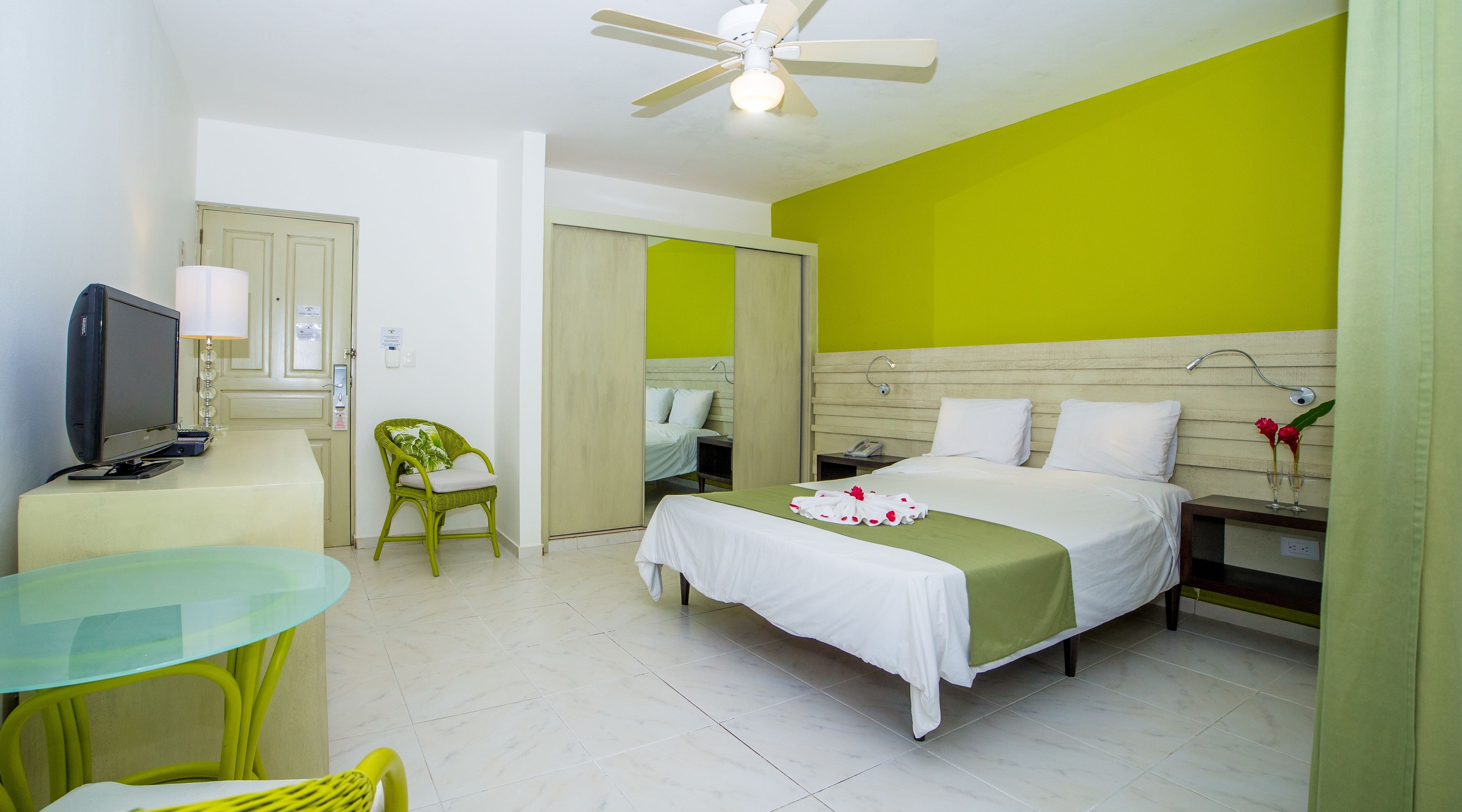 Una habitación de hotel con una cama, un escritorio con computadora, una silla y un televisor.