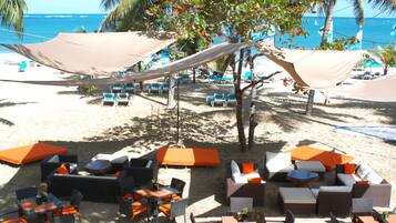 A beachside lounge area with outdoor seating and umbrellas, overlooking the ocean.