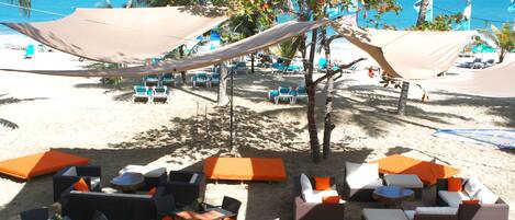 A beachside lounge area with outdoor seating and umbrellas, overlooking the ocean.