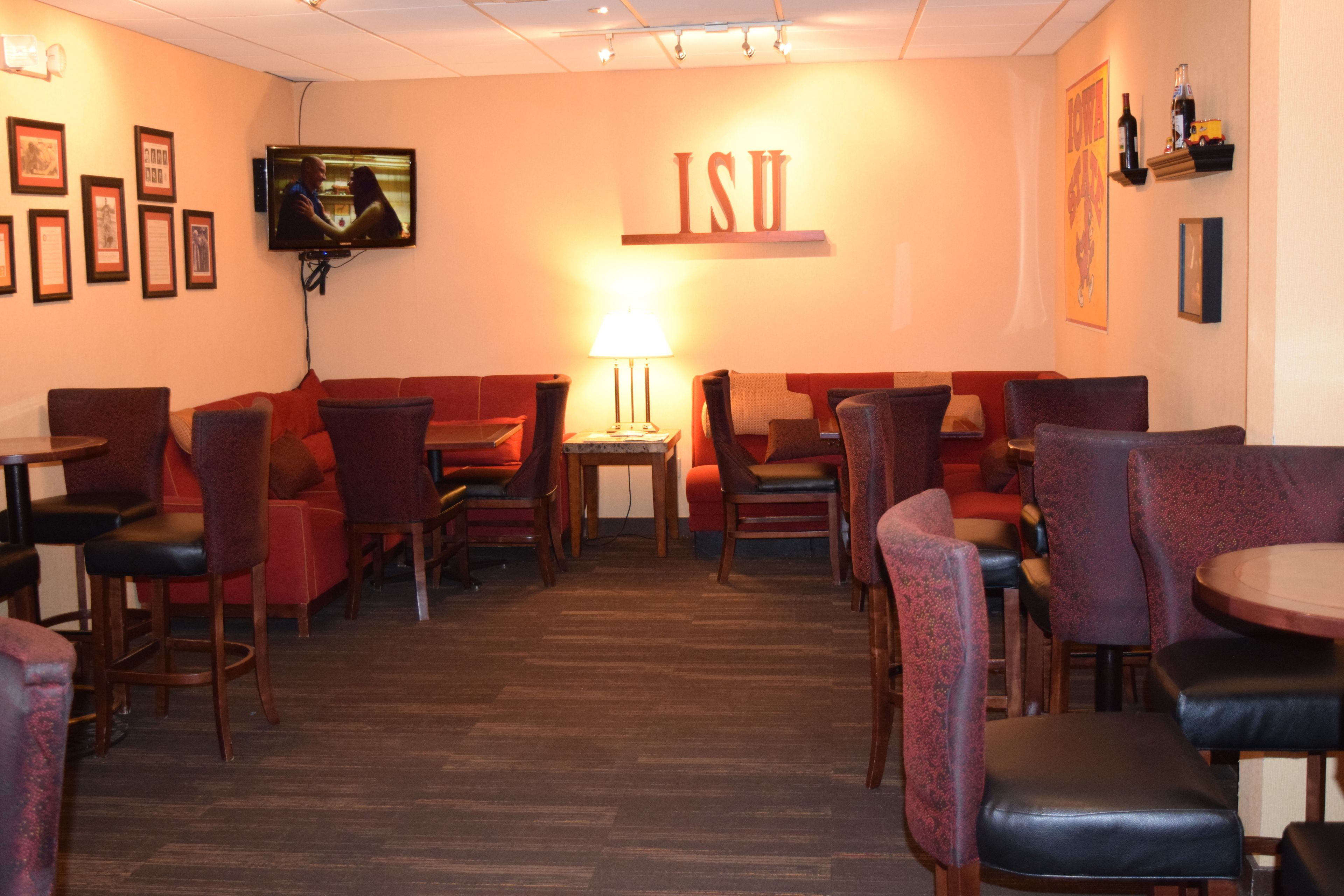 A restaurant with red upholstered booths, wooden tables, and a TV mounted on the wall.