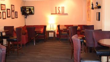 A restaurant with red upholstered booths, wooden tables, and a TV mounted on the wall.