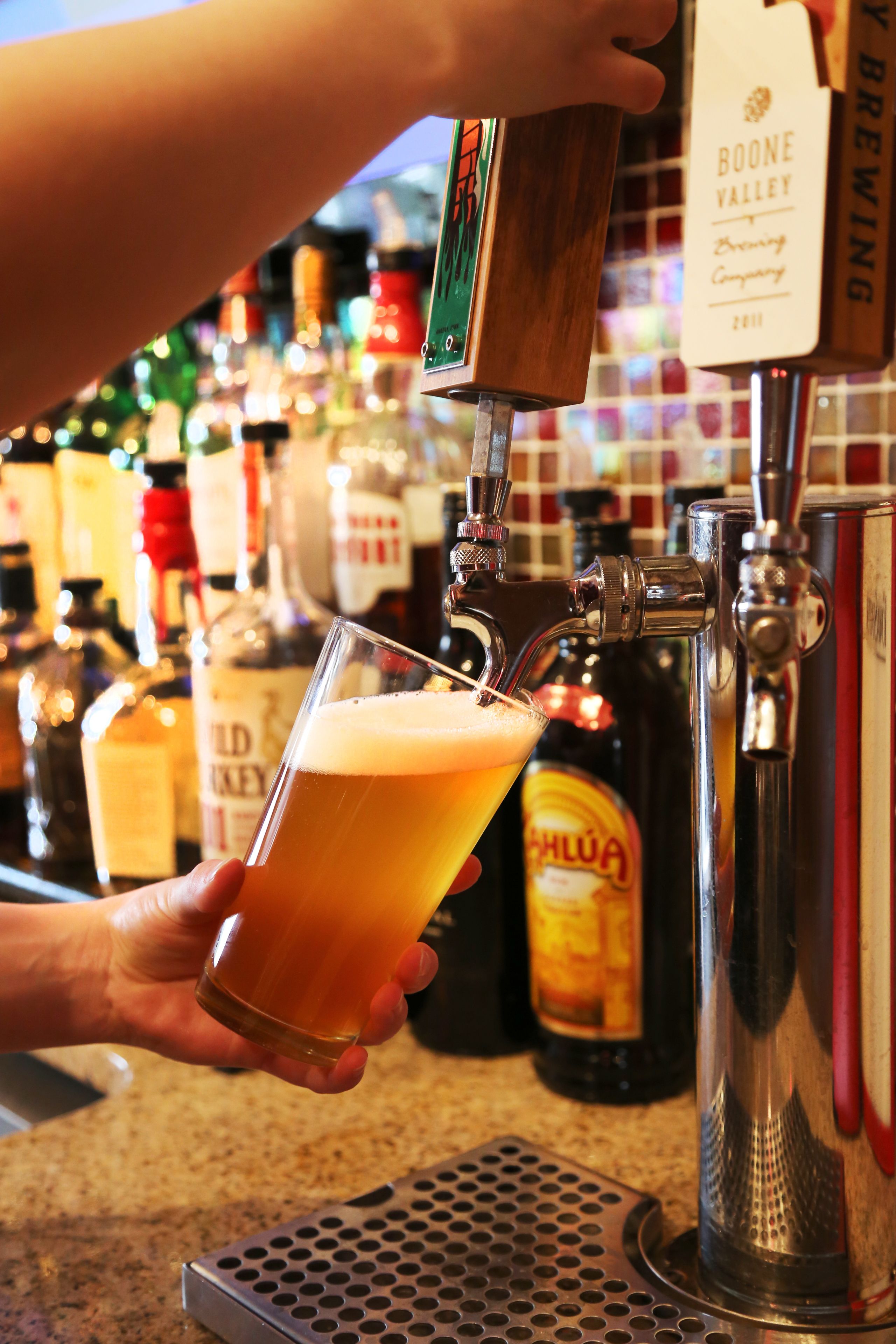 A bar setting with a beer tap and a glass of beer being filled.