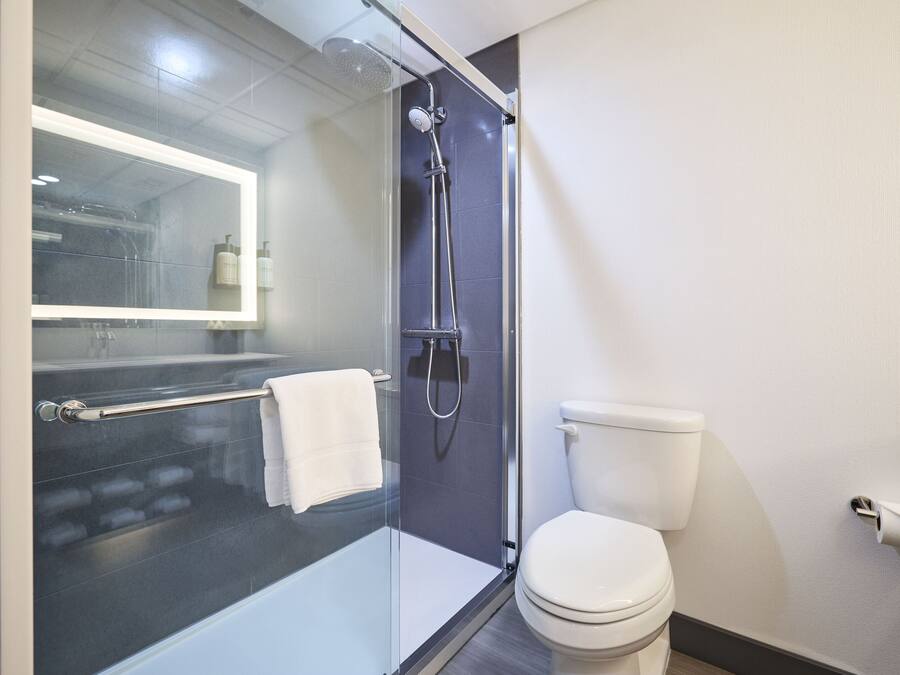 Un baño moderno con ducha envuelta en vidrio, inodoro blanco y bañera con cubierta de vidrio.