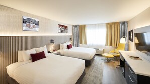 Une chambre d’hôtel avec deux lits, un bureau, une chaise et une télévision.