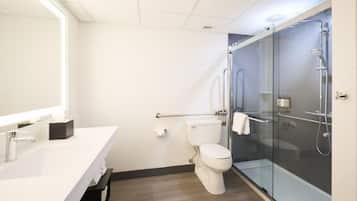 Un baño moderno con lavamanos blanco, cabina de ducha con mampara de vidrio y un inodoro.