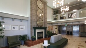 A spacious lobby with a fireplace, seating area, and a mezzanine level with a balcony. - Oxford Suites Spokane Valley (Spokane Valley)