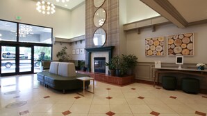 A lobby with a fireplace, seating area, and a reception desk. - Oxford Suites Spokane Valley (Spokane Valley)