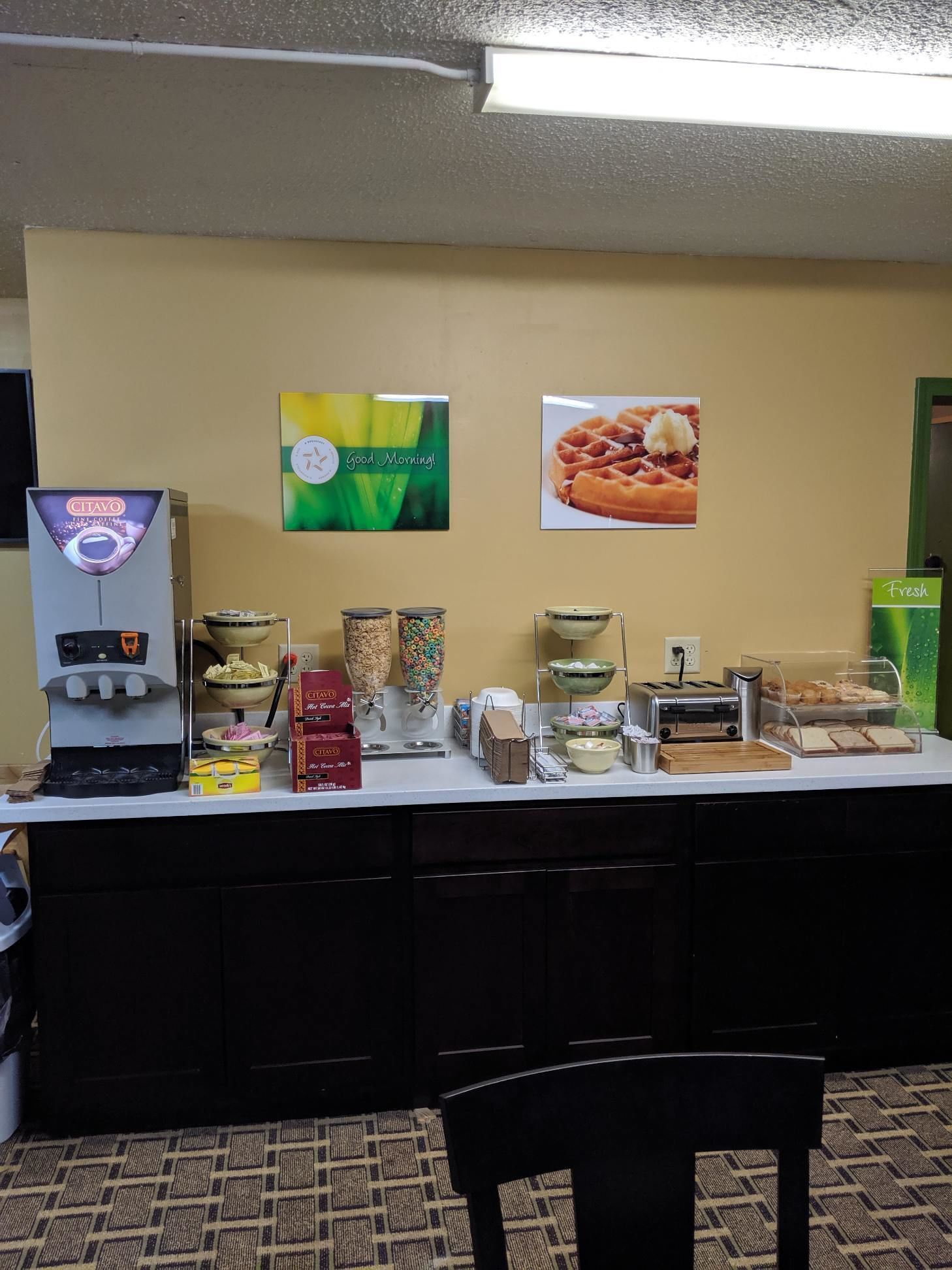 A breakfast bar with a coffee machine, cereal, and a waffle display.