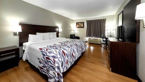 A hotel room with a large bed, bedside tables, a desk with a chair, a television, and a window with curtains. - Red Roof Inn Atlanta Southeast - Stockbridge (Stockbridge)