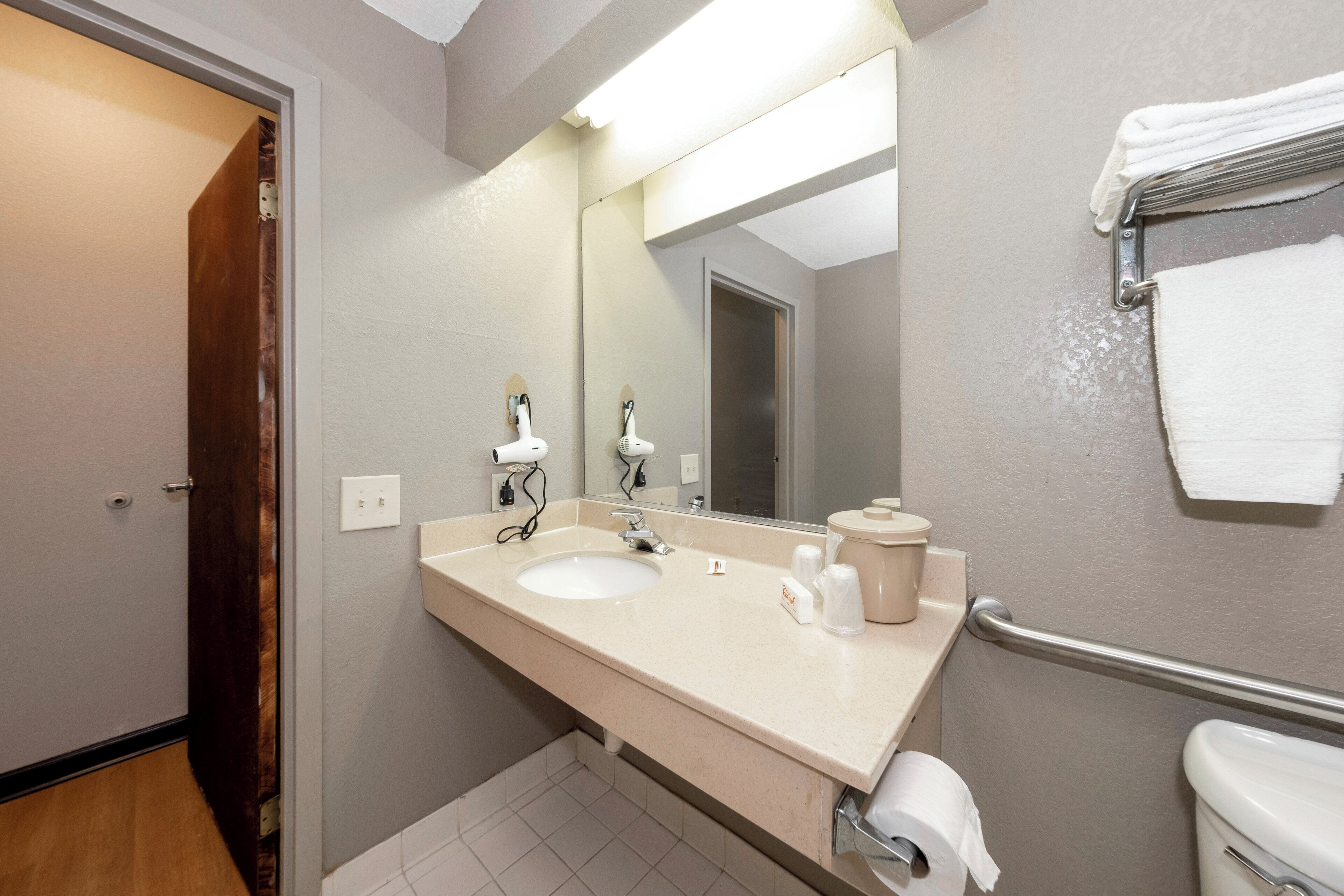 A bathroom with a sink, mirror, towel rack, and toilet.