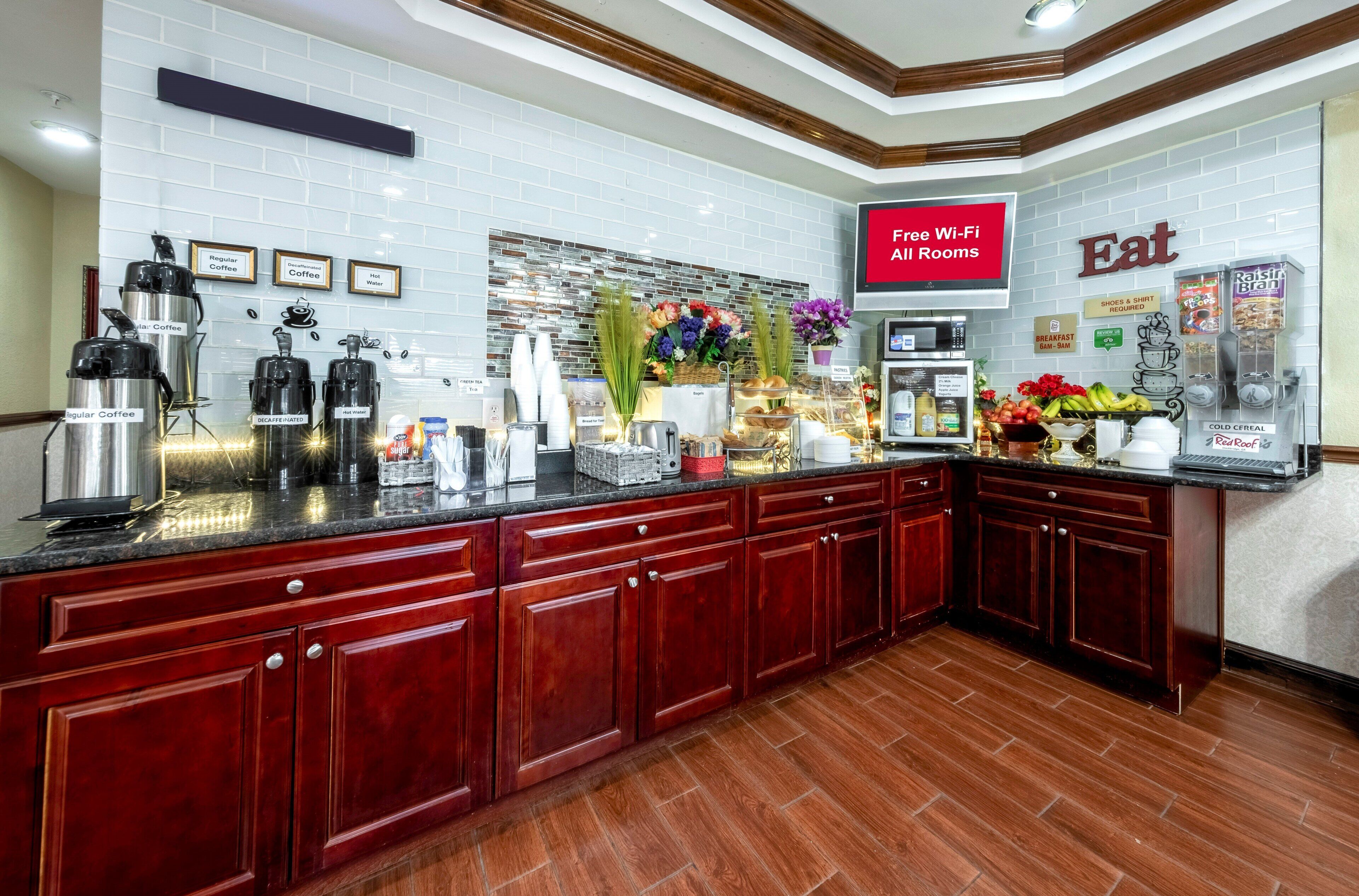 A modern kitchen with a coffee station, breakfast bar, and a sign indicating free Wi-Fi in all rooms.