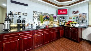 A modern kitchen with a coffee station, breakfast bar, and a sign indicating free Wi-Fi in all rooms.