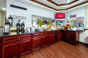 Una cocina moderna con estación de café, barra de desayuno y un cartel que indica Wi-Fi gratuito en todas las habitaciones.