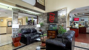 A hotel lobby with a black leather sofa, a fish tank, and a Red Roof Inn sign. - Red Roof Inn Atlanta Southeast - Stockbridge (Stockbridge)