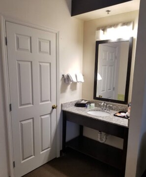 A bathroom with a white door, a sink with a mirror, and a towel rack. - Sleep Inn & Suites Orlando International Airport (Orlando)