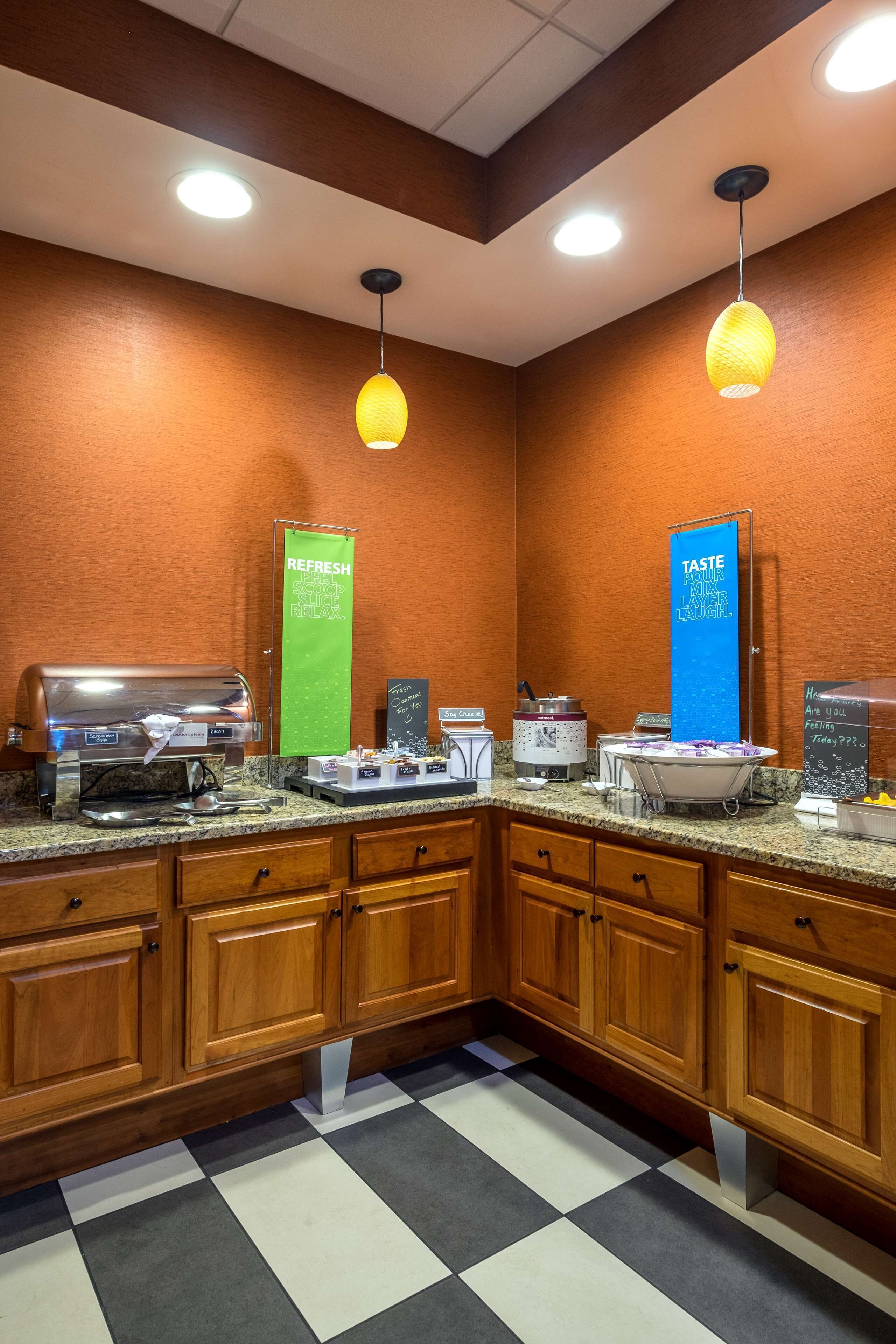Eine Hotelküche mit einem Buffet, darunter eine Kaffeestation, eine Getränkestation und verschiedene Speisen, die auf der Theke präsentiert werden.