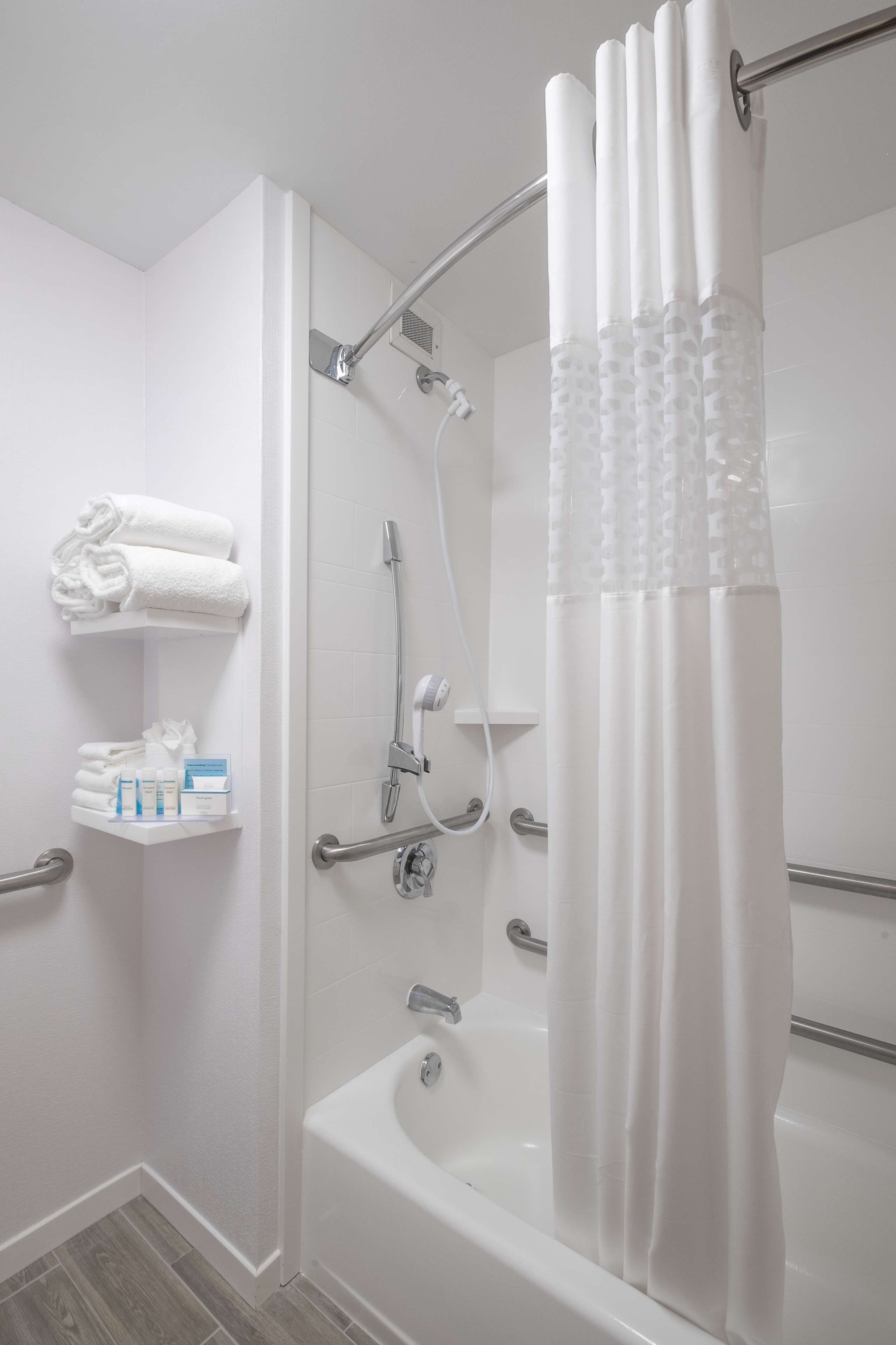 Un baño moderno con cabina de ducha, bañera y estante con toallas y artículos de aseo.