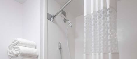 Un baño moderno con cabina de ducha, bañera y estante con toallas y artículos de aseo.