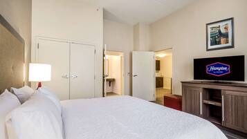 Quarto de hotel com cama grande, televisão e espaço com cozinha.