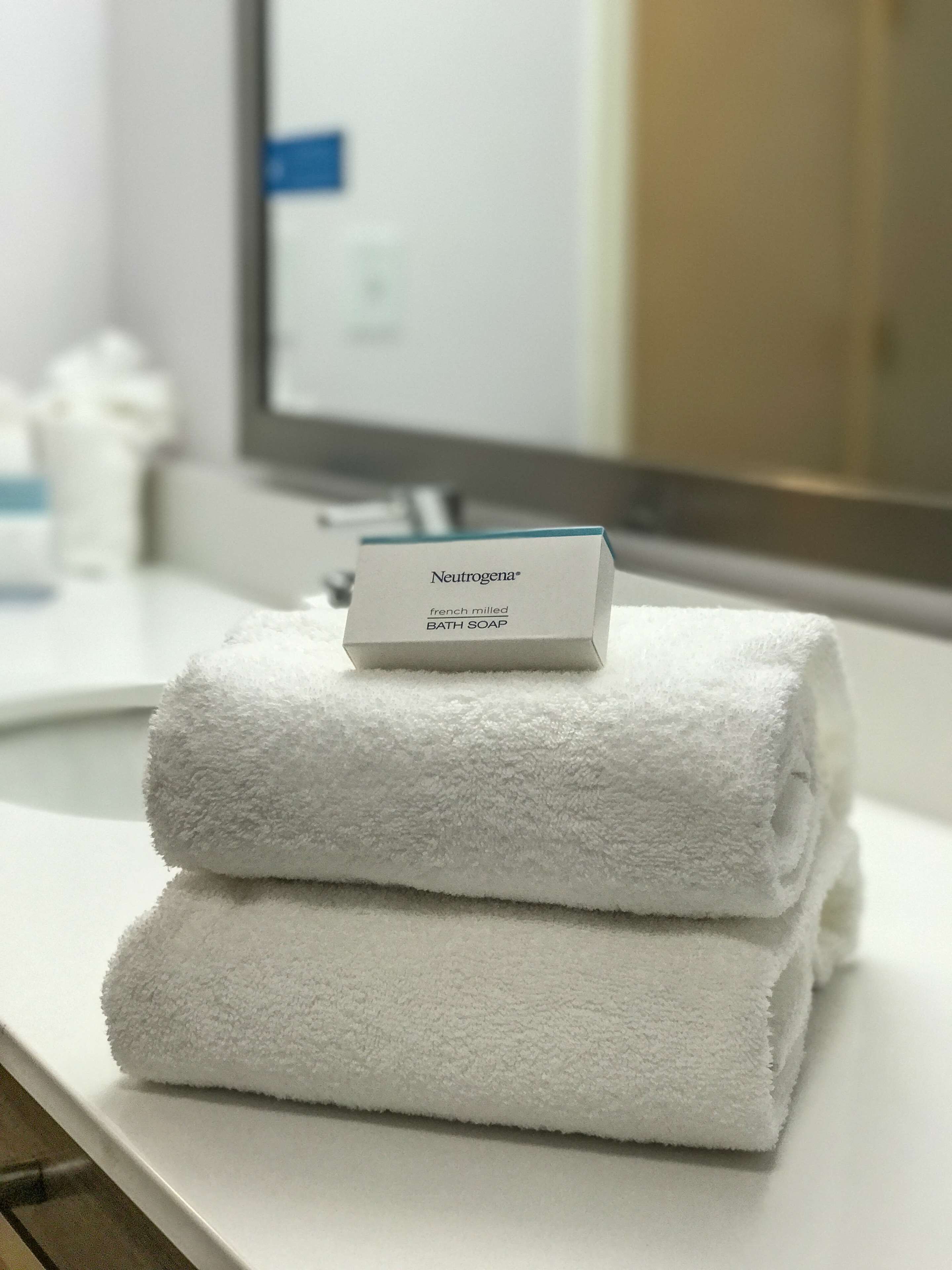 A stack of white towels on a bathroom counter with a Neutrogena® bath soap box on top.